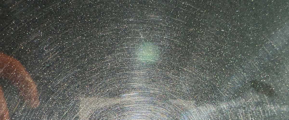 Swirl marks visible on dark car paint under direct light