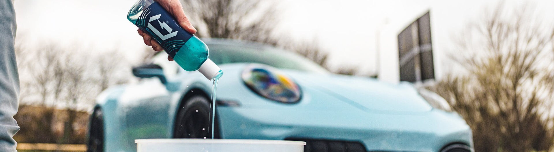 Measuring car shampoo into a wash bucket for the correct dilution
