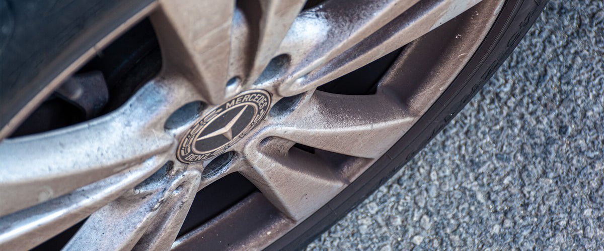 Close-up of a dirty alloy wheel showing brake dust and road grime