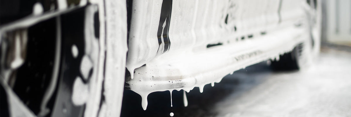 Close-up of snow foam clinging and dwelling on a car sill — showing cling and coverage