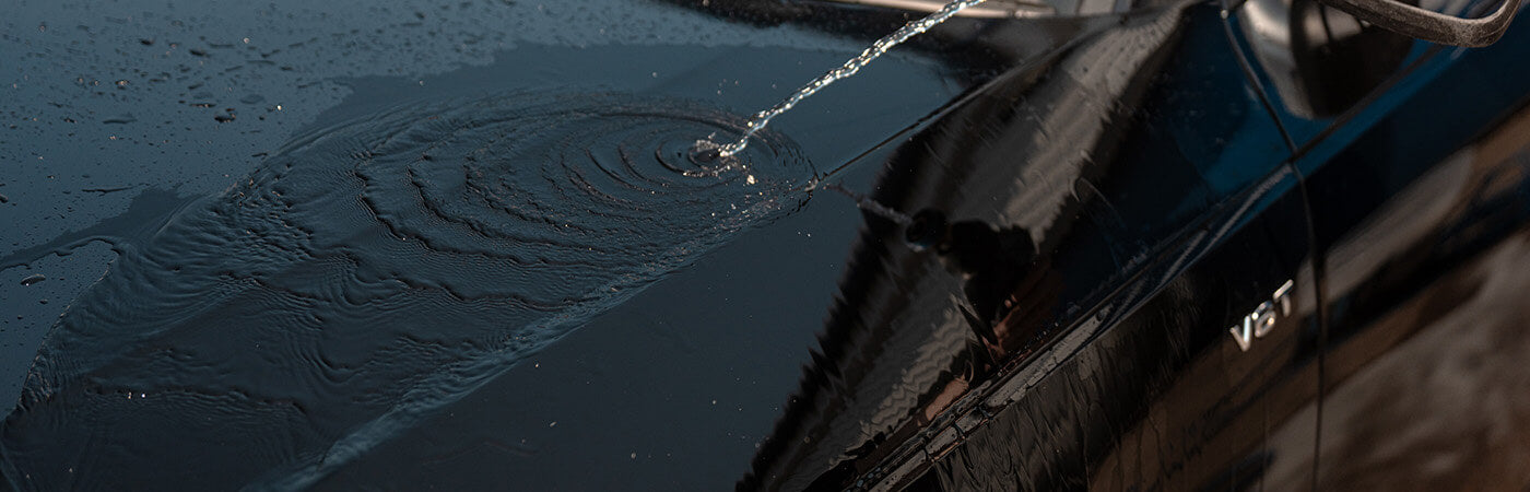 Water sheeting down a car bonnet during a rinse poured from a watering can