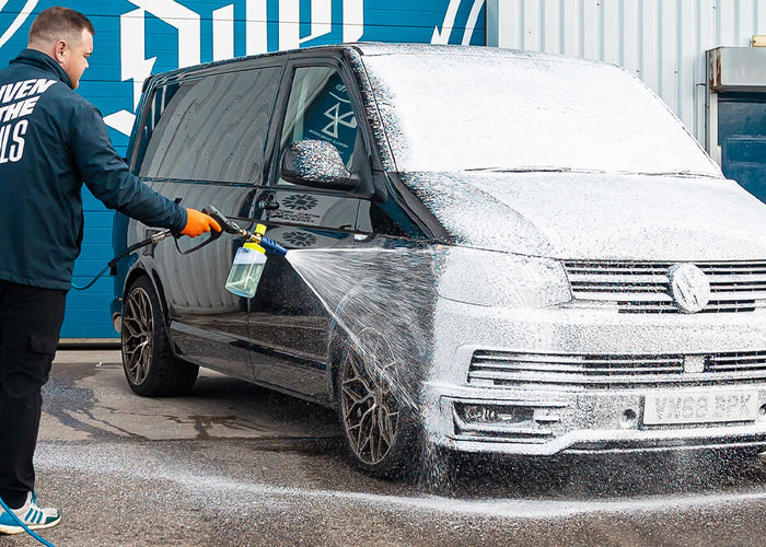Foam lance being used to apply snow foam to a car panel, showing product application